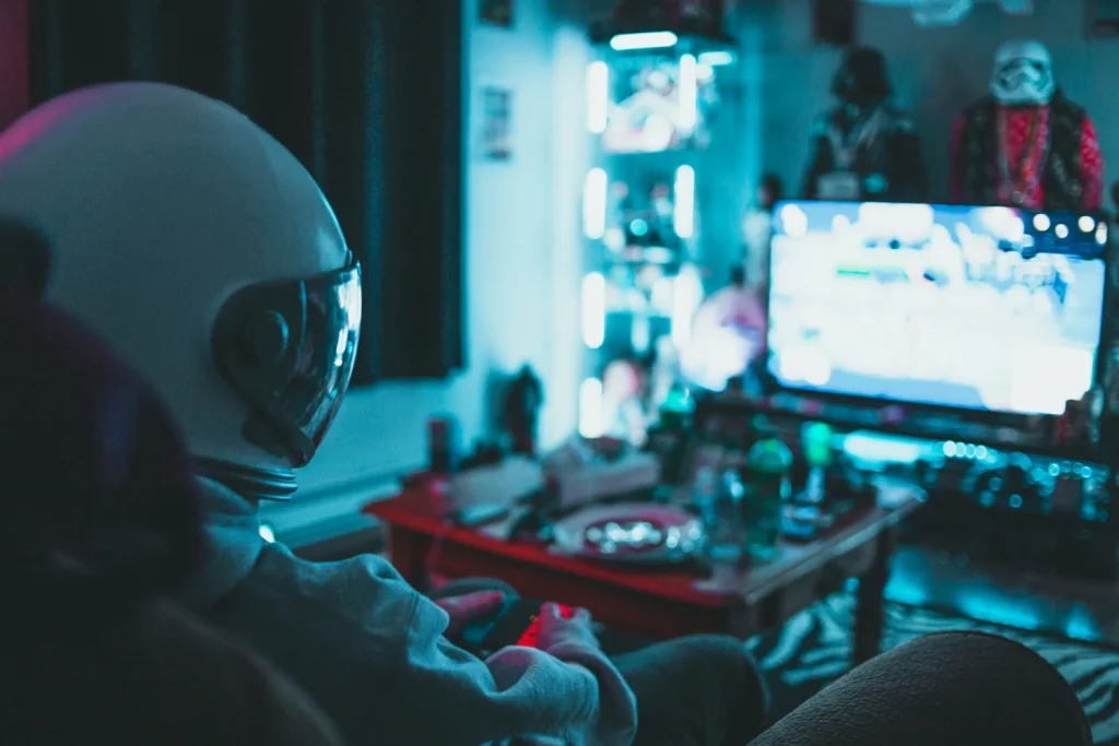 Person sitting in front of a screen holding a joystick, engaged in gaming