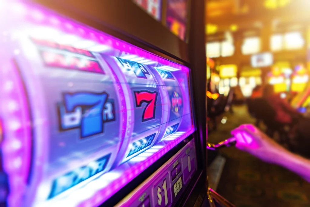 Person pressing a slot machine button, hitting two sevens and a BAR symbol.